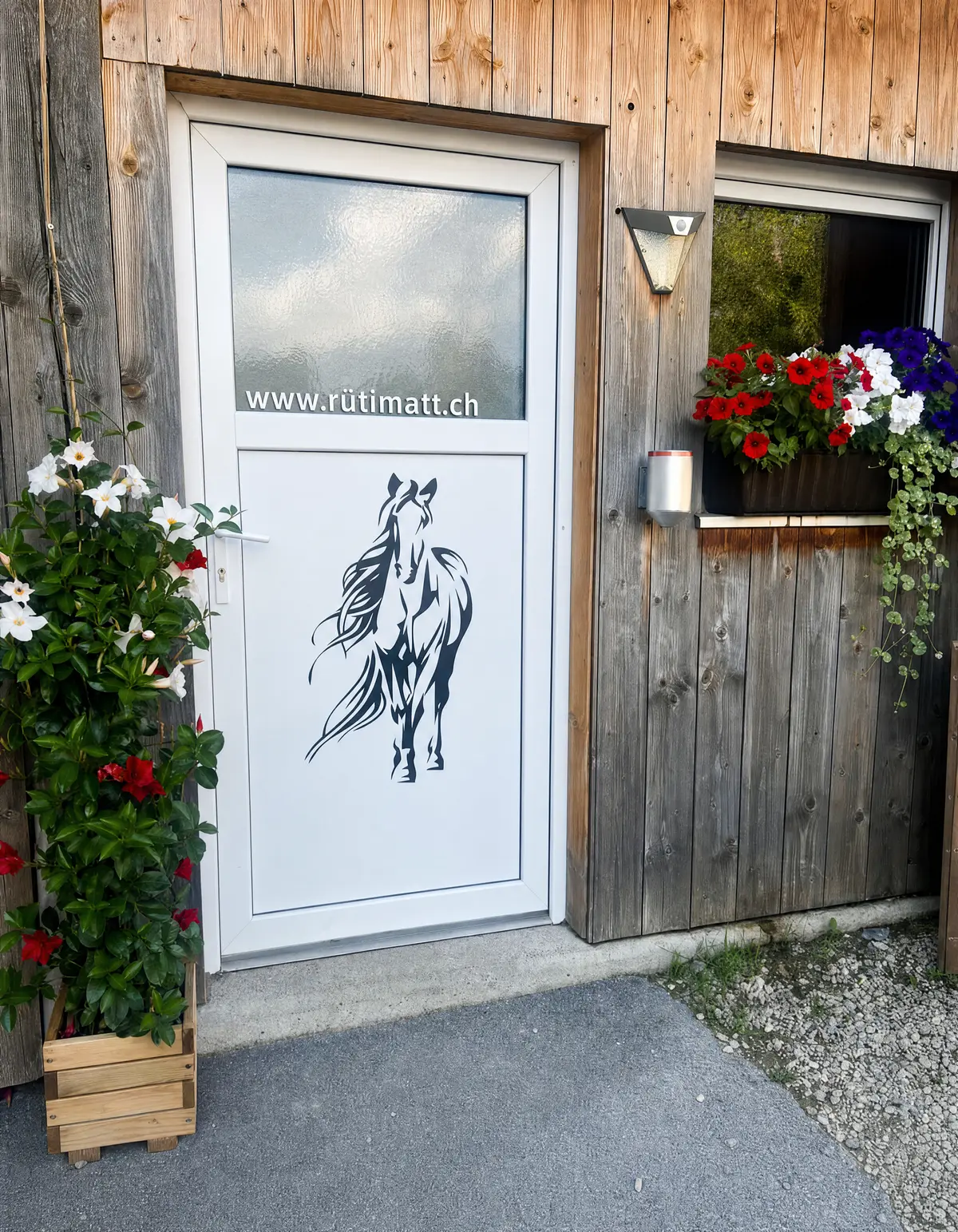 Eingang zum Reiterstübli mit Pferde-Dekor und Blumen